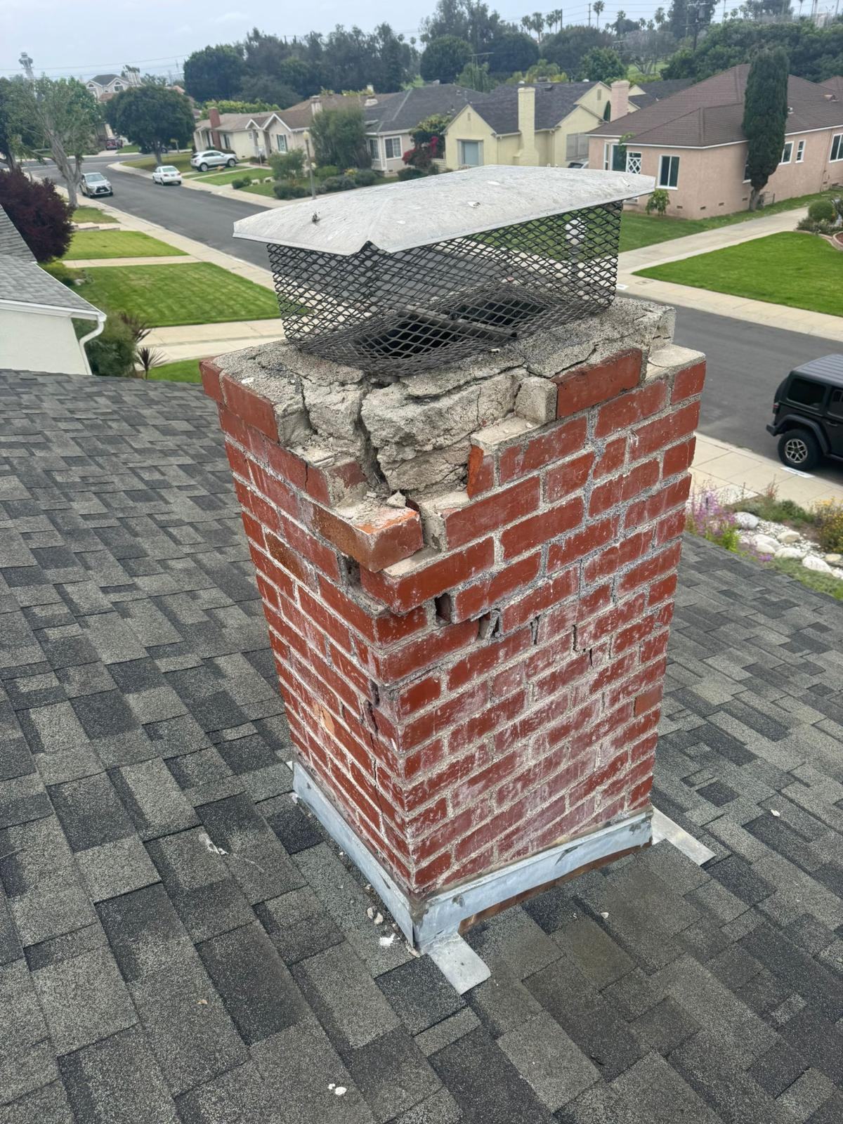 Damaged chimney with cracked crown and loose bricks, before repair